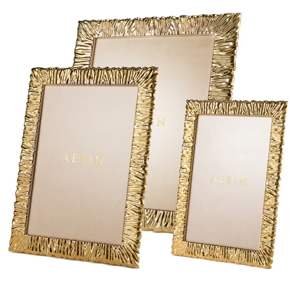 The AERIN Ambroise Frame Collection features three frames with textured borders, a luxurious brass-plated finish, and "Aerin" elegantly inscribed on the matte inside.