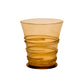 Introducing a tumbler from the Juliska Ella Drinkware Collection: amber-tinted artisan drinkware featuring a spiral, textured design wrapped around its exterior, expertly crafted in the signature mouth-blown style of Juliska and displayed against a plain white background.