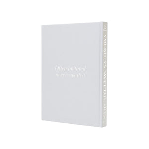 A white Assouline hardcover book titled "America's Sweethearts- Dallas Cowboys Cheerleaders" stands upright against a plain background, celebrating the iconic spirit and cultural impact of the famous cheerleading team.