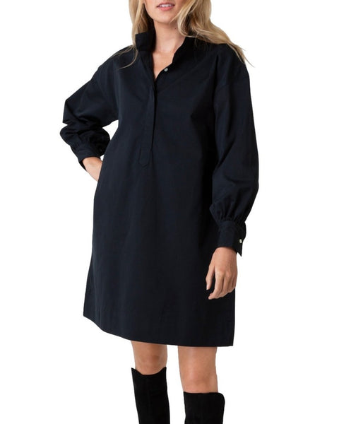 A woman wearing an Ann Mashburn Anaya Popover Dress with long sleeves paired with black boots, standing against a white background. Her face is not visible.