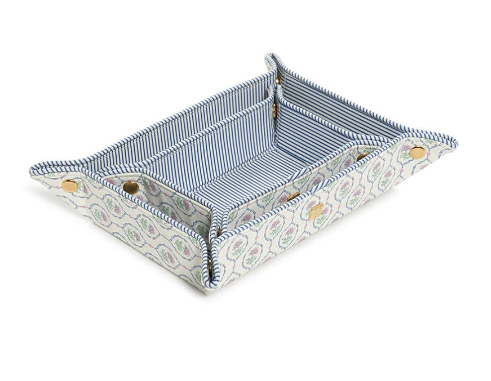 From TRVL Design’s Luxe Saffiano Tray Set Collection, this pocket-sized rectangular fabric tray features raised sides, a striped blue-and-white interior, paisley-patterned exterior, and gold snap buttons—perfect as a travel valet.