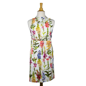 Caspari Apron Collection: Sleeveless cotton apron with a vibrant floral print and green leaves on white—ideal as a stylish kitchen accessory.