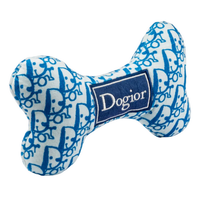 The Dogior Bone by Haute Diggity Dog is a blue and white dog bone-shaped plush toy featuring a repeating blue pattern and a “Dogior” label in the center; this luxury dog toy delivers designer style along with a hidden squeaker inside for extra fun.