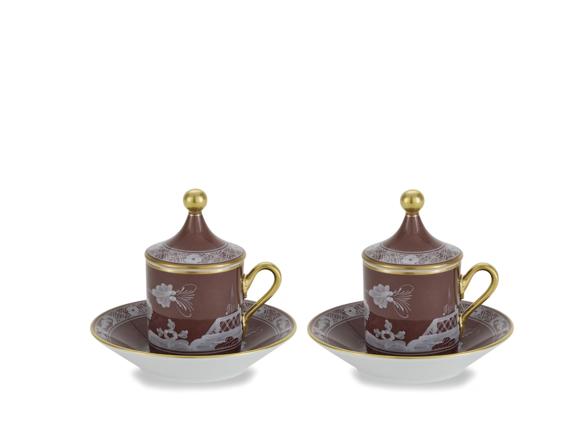 Two matching Oriente Italiano Castagna Decor Collection porcelain cups with lids and saucers by Ginori 1735, adorned with brown and gold accents and floral patterns, are displayed against a white background.