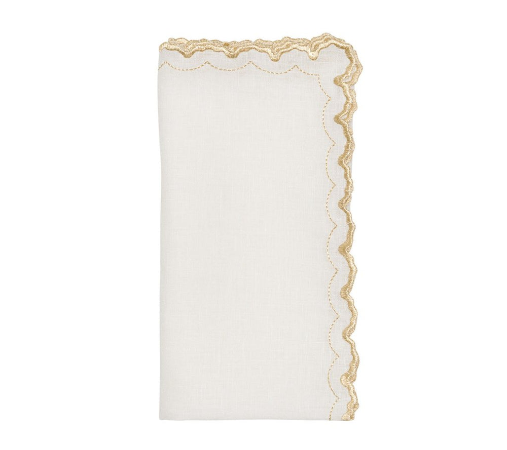 The Kim Seybert Arches Napkin Set features white linen napkins folded vertically with a scalloped, gold-embroidered edge—an elegant touch for formal dining.
