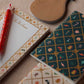 Two Holiday Argyle Pocket Notebooks with festive patterns featuring holiday icons, alongside a red patterned pen, a wooden ornament, and gold foil accents.