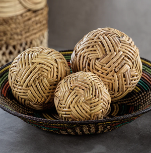 The Zodax Rattan Fill Ball Collection features three intricately braided rattan balls in different sizes, arranged in a woven basket for a natural, decorative touch.
