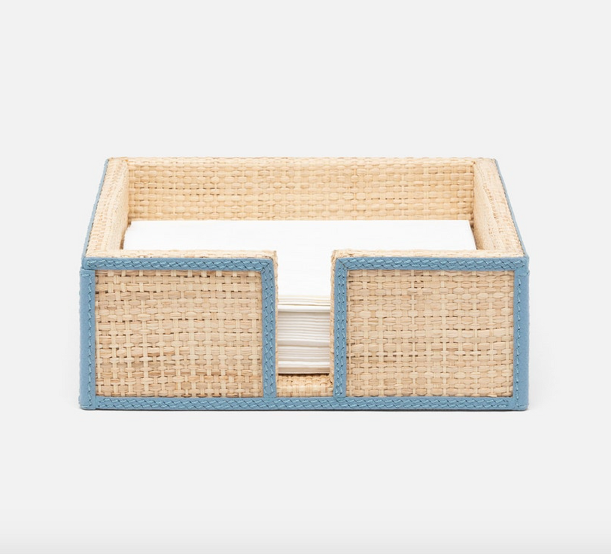 A woven rectangular napkin holder from the Gable Natural/White Barware Collection by Blue Pheasant with light blue leather trim holds a stack of white napkins, shown front view.