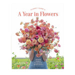 A person holds a large bouquet of pink and orange flowers in front of their face, showcasing the stunning floral design featured on the cover of “A Year in Flowers” by Chronicle Books.
