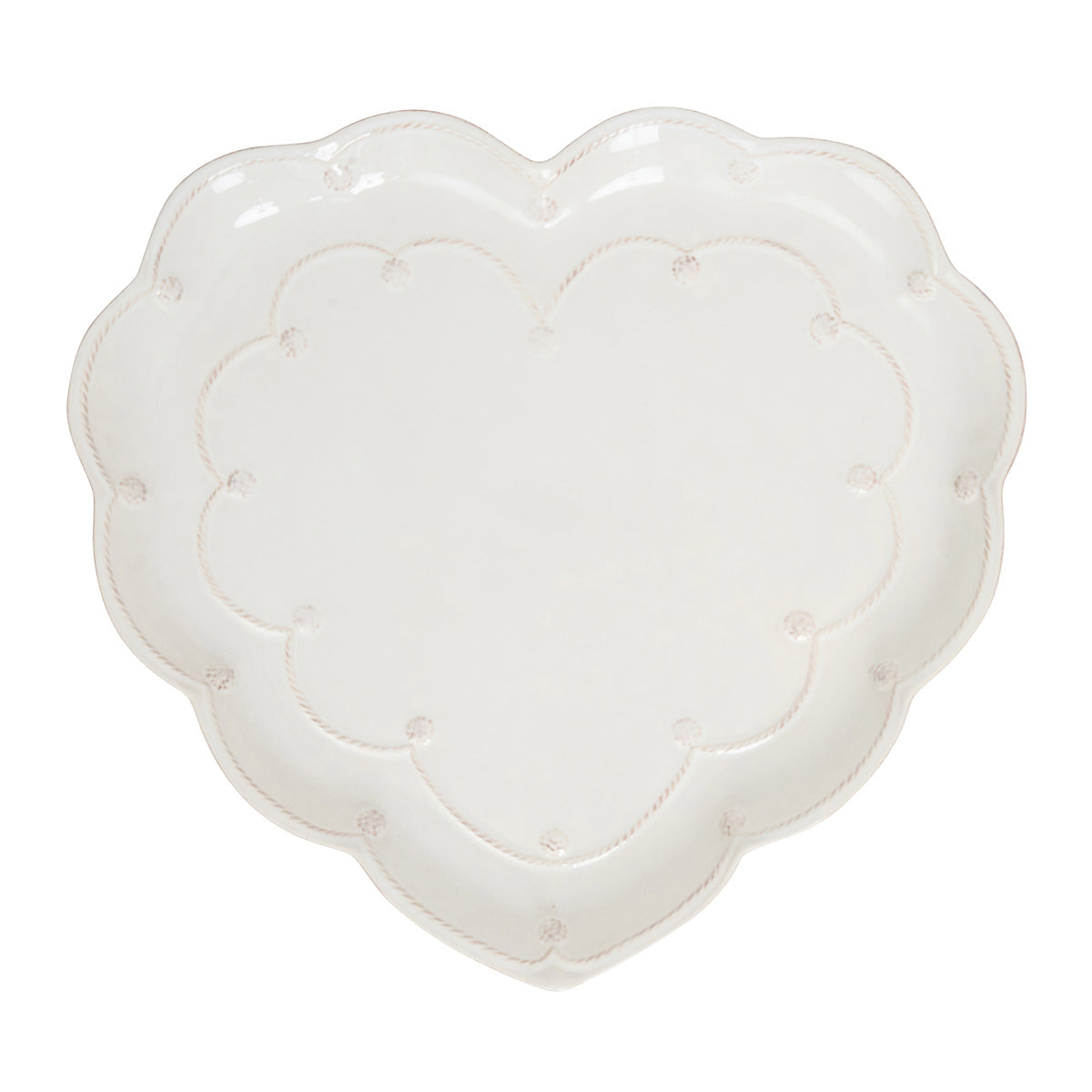 The Juliska Berry & Thread Whitewash Heart Serveware Collection features a white ceramic heart-shaped platter with a ruffled rim and delicate dotted and ridged detailing around the edge.