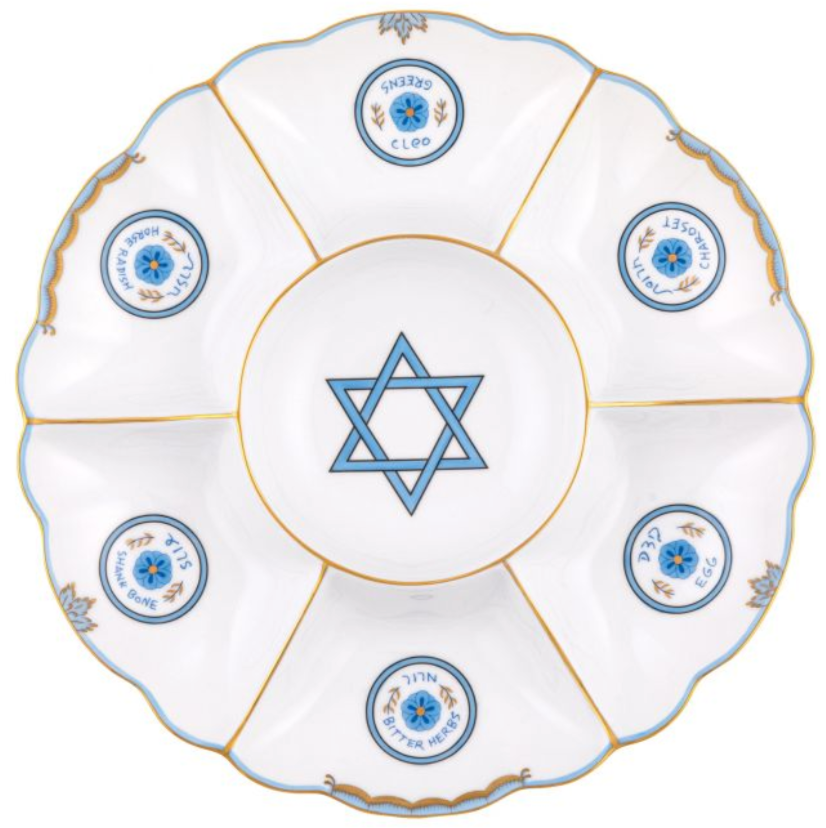 The Herend Fish Scale Seder Plate, Blue, showcases a stunning design with hand-painted white and blue elements, Hebrew text, and a Star of David centerpiece. Crafted from Herend porcelain, it features six sections for the symbolic foods.