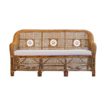 The Julianna Sofa by Varnish Collection is a handmade wicker loveseat with natural materials, a decorative woven backrest with three circular patterns, and a light cushion.
