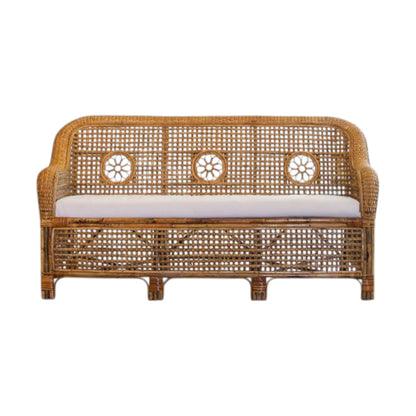 The Julianna Sofa by Varnish Collection is a handmade wicker loveseat with natural materials, a decorative woven backrest with three circular patterns, and a light cushion.