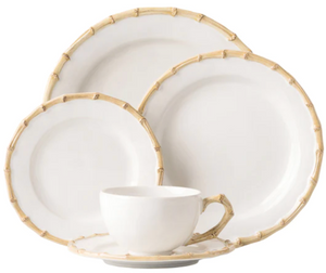 The Classic Bamboo Dinnerware Collection by Juliska features white ceramic pieces with bamboo-patterned rims for casual elegance. Set includes dinner plate, salad plate, bread plate, cup, and saucer.