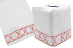The Bamboozle Bath Collection by Haute Home showcases a white cloth tissue box cover made from exquisite Italian linen, adorned with a hand-embroidered geometric pink and white border design, depicted from side and angled views.