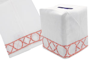 The Bamboozle Bath Collection by Haute Home showcases a white cloth tissue box cover made from exquisite Italian linen, adorned with a hand-embroidered geometric pink and white border design, depicted from side and angled views.
