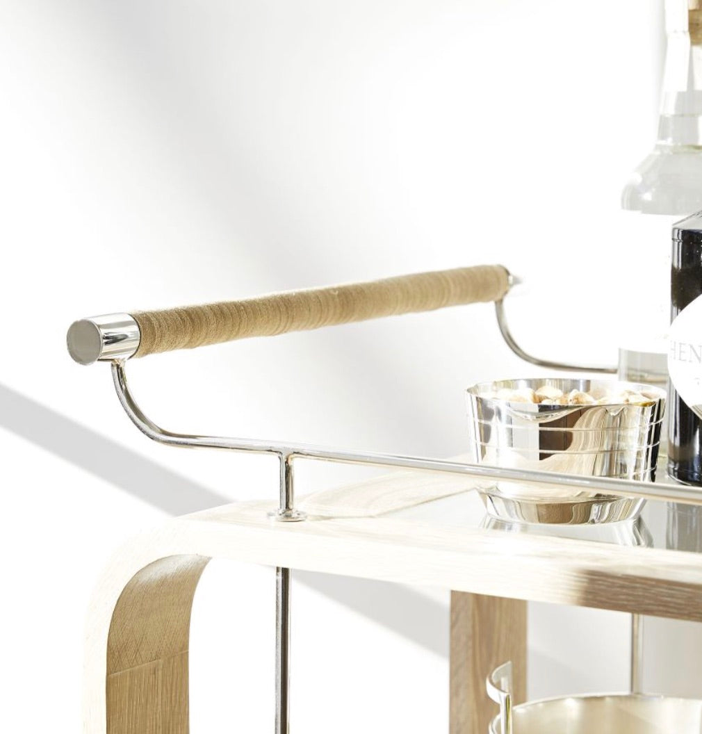The Brays Bar Cart by Arteriors features a leather-wrapped handle, sleek metal frame, glass shelf, and ample space for drinks and snacks—an elegant choice for your next cocktail party.