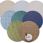 Eight Chilewich Round Placemats made from phthalate-free Terrastrand yarns overlap in a circle, with a white cup, saucer, and red spoon placed on the bottom right placemat.