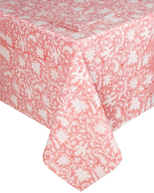 The Madrid Table Linen Collection by SLOANE BY HAND features a pink and white floral fabric that elegantly drapes over the sides and corners of a rectangular table.
