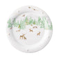 The Berry & Thread North Pole Dinnerware and Serveware Collection by Juliska features a white plate with a winter forest scene, green trees, gold reindeer, and Santa’s sleigh—ideal festive dinnerware for your holiday gatherings.
