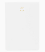 The Sugar Paper Mini Notepad, Smiley, features a petite white design with a cheerful yellow smiley at the top—perfect for brightening your notes.