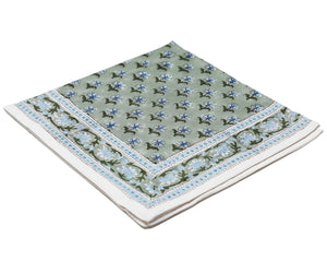 The Alwar Table Linen Collection by SLOANE BY HAND features a neatly folded square handkerchief with a green background, blue and white floral pattern, and decorative border—ideal for pairing with napkin sets or floral tablecloths.