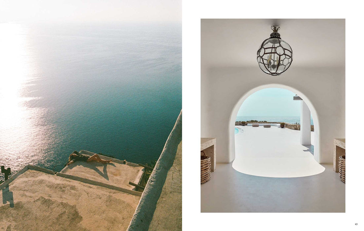 A person enjoys barefoot luxury, sunbathing on a Beach House cliffside ledge next to an arched doorway framing a coastal patio and the ocean.