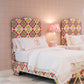 Two EJ Schrader Rosa Spring Twin XL Beds with floral headboards and white bedding sit side by side in a pink-walled bedroom, complemented by playful furniture, a nightstand, and a lamp between them.