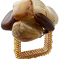 The Kim Seybert Sea Stone Napkin Ring features a square design, beaded gold-tone band, and polished brown and beige beach stones clustered on top—an elegant accent for your table setting.