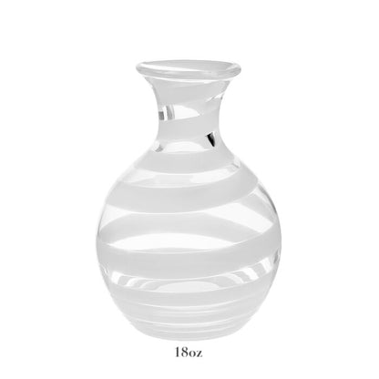 The Bella Bianca Carafe Collection by William Yeoward Crystal features a clear glass carafe with white stripes, round body, narrow neck, and flared rim. Shown on white background with "18oz" below. Proposition 65 warning applies; ideal for serving wine.