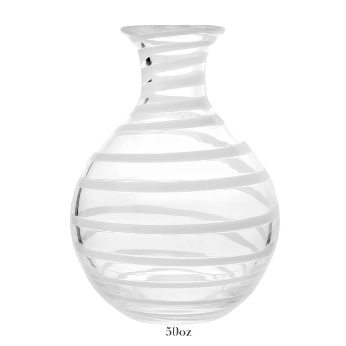 The Bella Bianca Carafe Collection by William Yeoward Crystal features a clear glass carafe with a round base, narrow neck, diagonal white stripes, and 50-oz capacity—perfect for wine. Proposition 65: may expose you to chemicals causing harm in California.