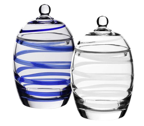 The William Yeoward Crystal Bella Candy Jar Collection includes two handmade glass jars with lid knobs: one with blue spiral stripes and another clear with white stripes. Their crystal glass design adds elegance to any setting, ideal for use as candy jars.