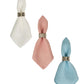 The Berry Scallop Napkin Set by Juliska features three linen napkins in white, pink, and blue with silver rings. Expertly woven in Portugal, they add elegance to any table.