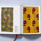 The Book of Printed Fabrics by Taschen lies open, revealing vibrant abstract designs: small motifs on yellow on the left page and red fans on the right—a striking tribute to fabric printing’s artistic heritage.