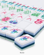 The Oh My Mahjong Tile Collection from Oh My Mahjong features hand-painted tiles with vibrant designs like flowers and symbols, topped off by a prominent joker tile showcasing a bird motif to enhance your gaming experience.