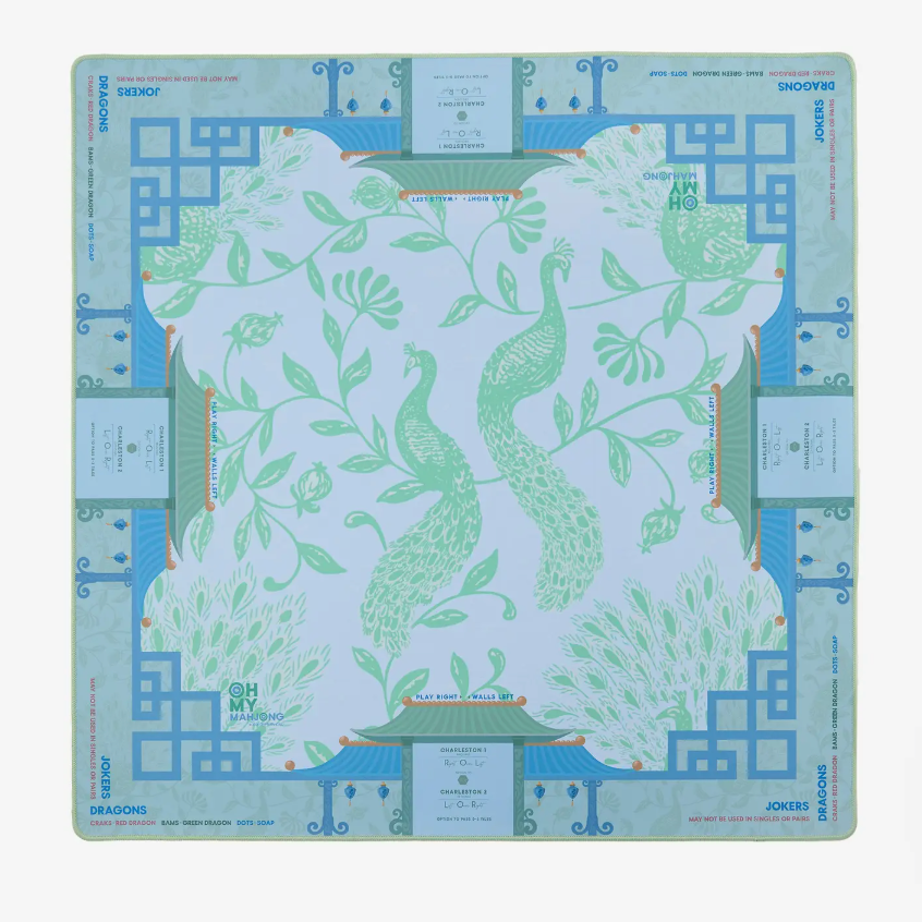 Introducing the Mahjong Mat Collection by Oh My Mahjong—a square game board featuring two green peacocks amid leafy surroundings, complemented by geometric blue border patterns and clearly marked card game areas on each side. Expertly crafted from high-quality neoprene for a non-slip surface, this stylish mat keeps your tiles securely in place throughout every round.