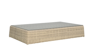 The Zeya Grande Outdoor Coffee Table by Janus et Cie features a glass top and a light beige, weather-resistant woven rattan base, displayed against a plain white background.