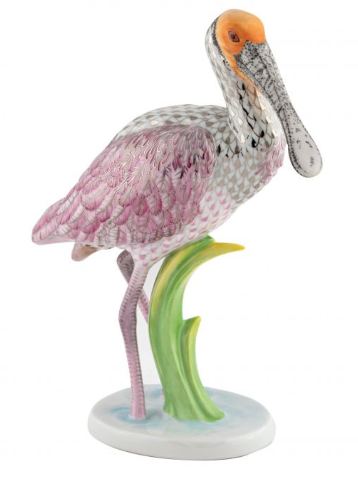 The Herend Reserve Collection Roseate Spoonbill is a porcelain figurine featuring vibrant pink feathers, an orange head, and a long beak poised above green reeds—capturing the bird’s delicate beauty in fine detail.