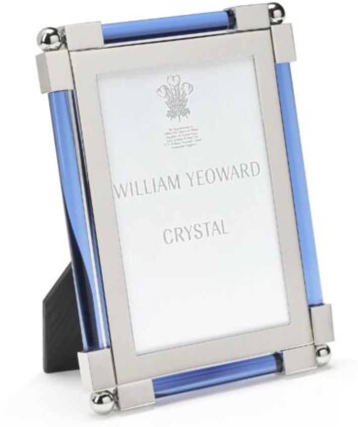 The Light Blue Classic Frame Collection by William Yeoward Crystal features a rectangular, nickel-plated photo frame with silver metal edges and blue glass accents; this classic item may carry a Proposition 65 warning.