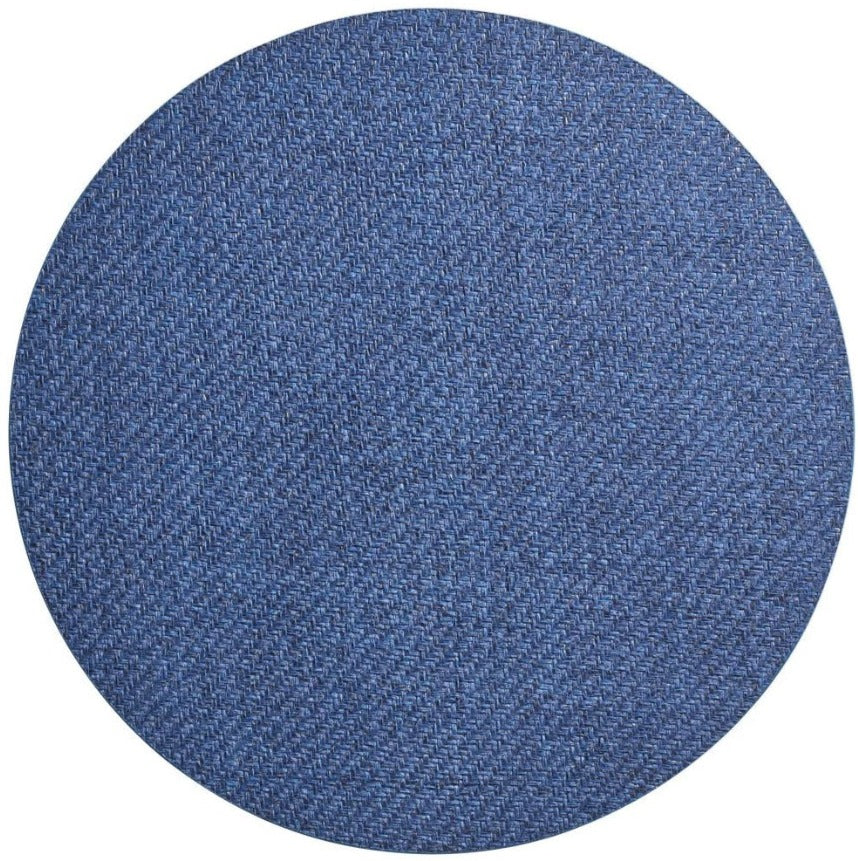 A round swatch of blue denim fabric shows the woven texture of the Kim Seybert Saigon Placemat, echoing patterns inspired by Vietnamese plaiting.