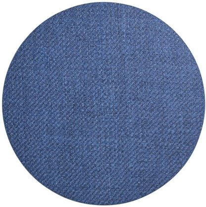 A round swatch of blue denim fabric shows the woven texture of the Kim Seybert Saigon Placemat, echoing patterns inspired by Vietnamese plaiting.