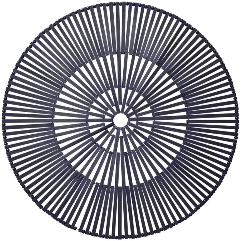 The Kim Seybert Spoke Placemat features a circular black design with evenly spaced radial spokes that create a bold geometric pattern, all converging at a small central hole.
