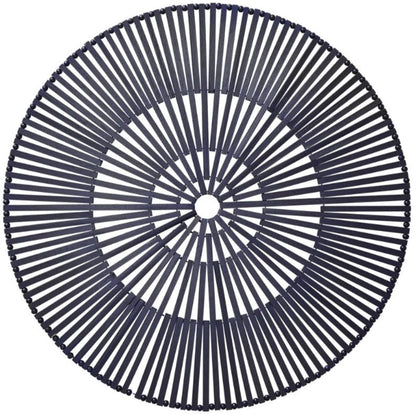 The Kim Seybert Spoke Placemat features a circular black design with evenly spaced radial spokes that create a bold geometric pattern, all converging at a small central hole.