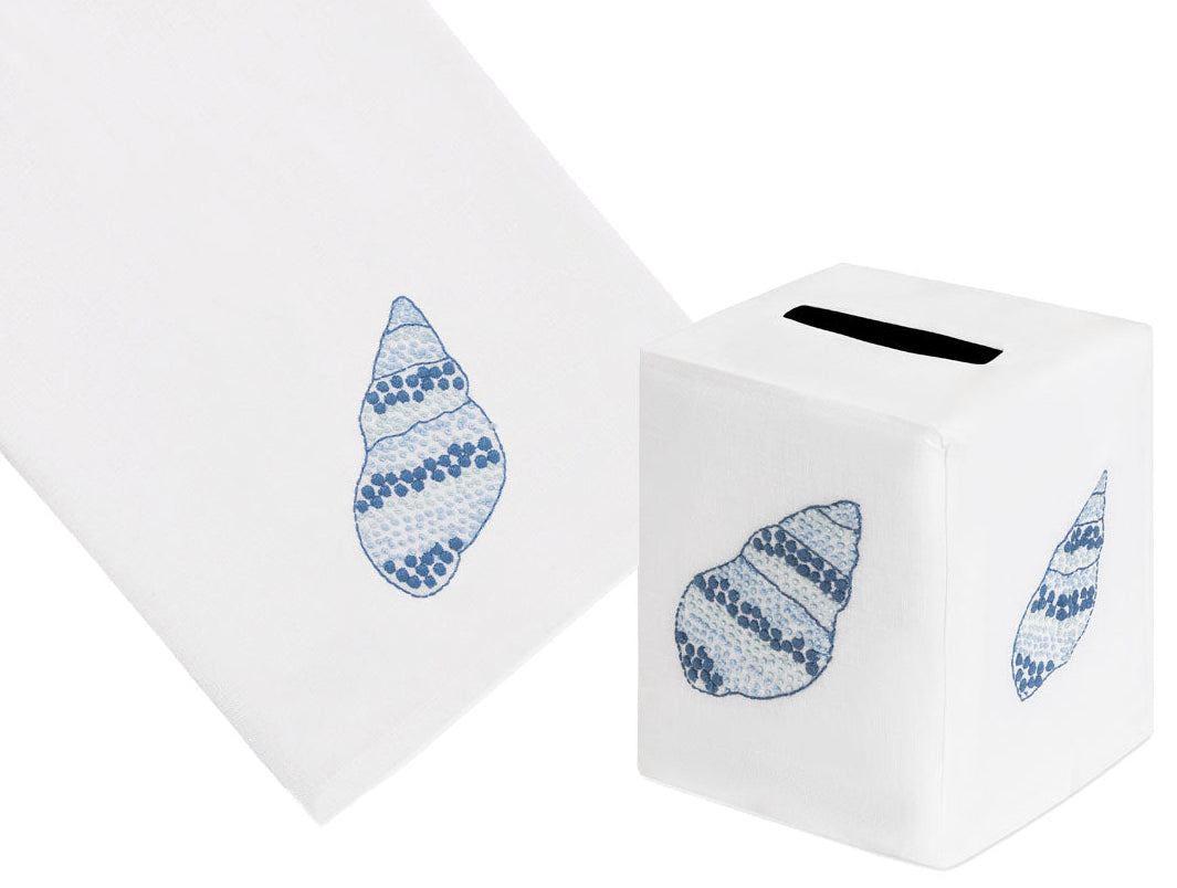The Haute Home Speckled Conch Bath Collection in Blue features a white Italian linen tissue box cover and hand towel, each beautifully hand-embroidered with a blue seashell design.