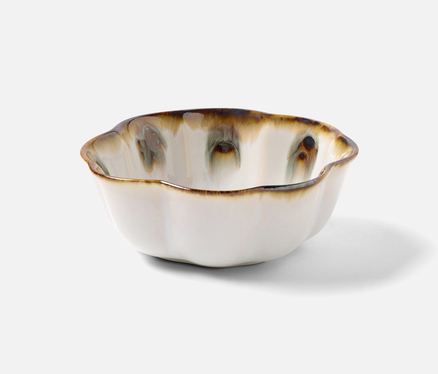 The Amoria Dinnerware Collection by Blue Pheasant features a ceramic bowl with a wavy rim, cream-colored reactive glaze, and brown-blue accents near the edge, offering vintage-inspired elegance displayed on a plain white background.