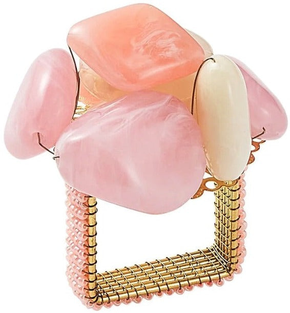 The Kim Seybert Sea Stone Napkin Ring is a square gold wire napkin ring topped with clusters of polished pink and white stones, evoking the look of delicate beach pebbles.