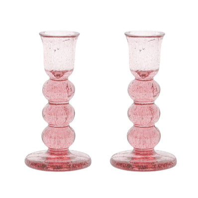 The Juliska Provence Candlestick Set features pink glass holders with a rounded, stacked design and wide base—perfect for adding vibrant color to your decor.