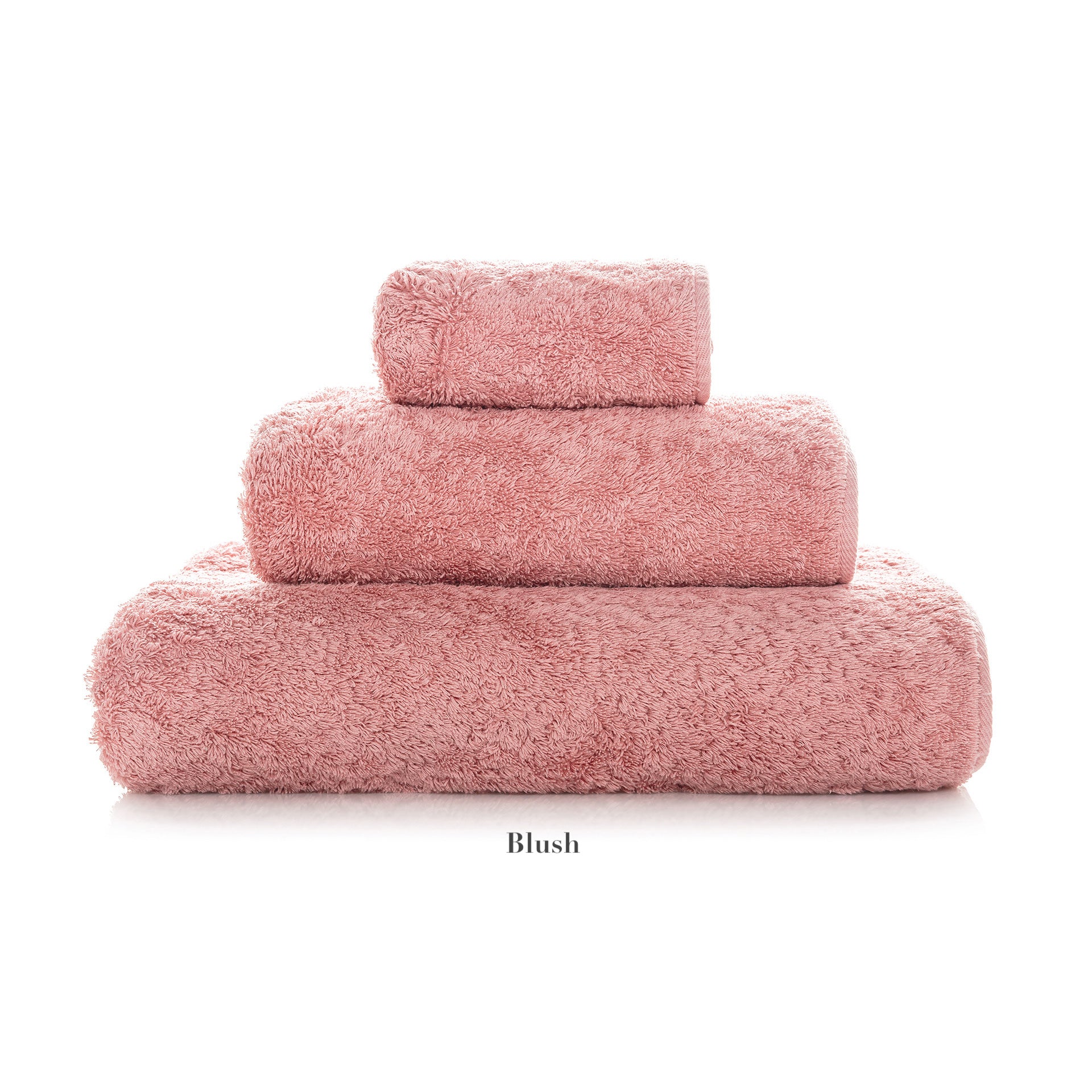 A stack of three blush pink towels from the Egoist Bath Collection by Graccioza, crafted from luxurious Egyptian cotton in varying sizes and arranged largest to smallest, sits on a white background.