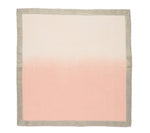 The Kim Seybert Dip Dye Napkin Set by Kim Seybert features a square cloth with an autumnal gradient design, transitioning from light pink at the bottom to beige at the top, bordered by a gray edge.