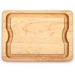 The J.K. Adams Maple BBQ Cutting Board features a rectangular shape, recessed groove, and indented sides for grip, shown against a white background.